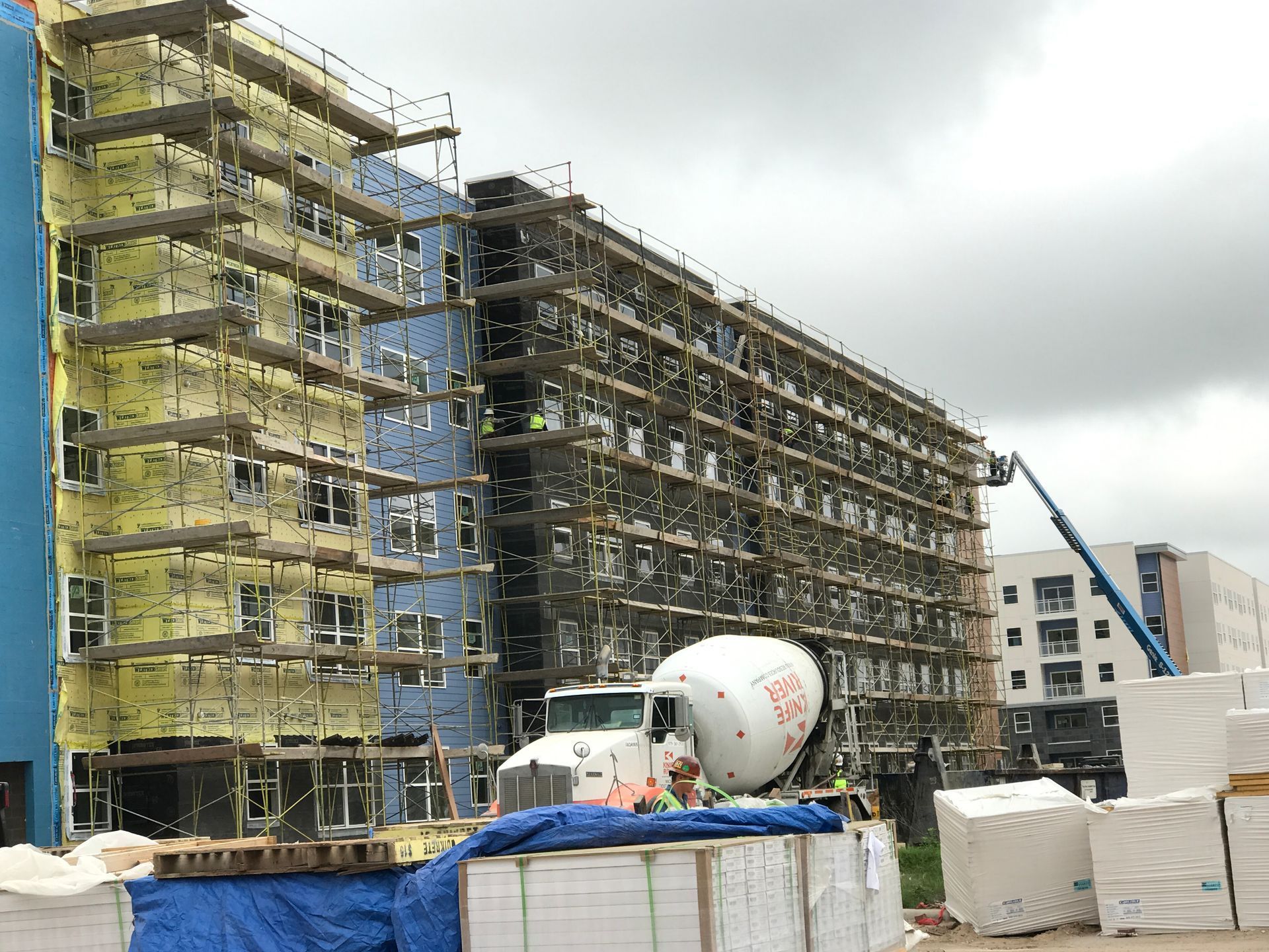 A large building under construction with a concrete mixer in front of it.
