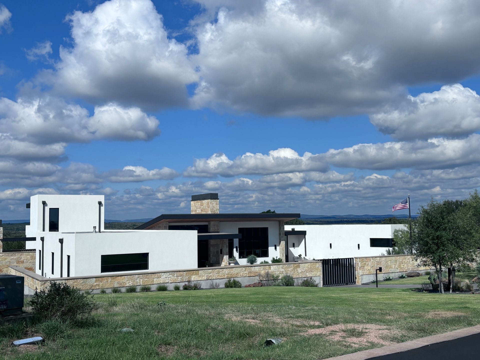 A large white house is sitting on top of a lush green hillside