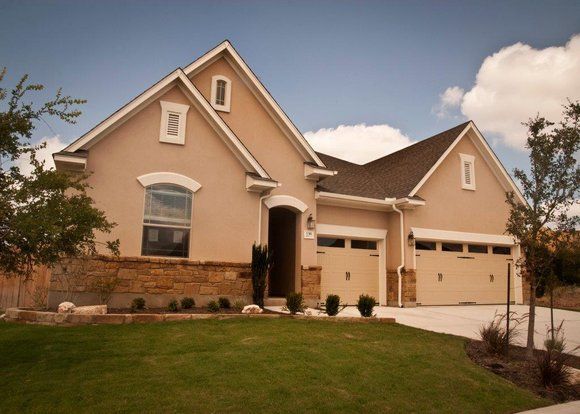 A house with two garage doors and a lush green lawn