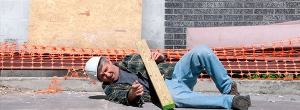 Construction worker lying on the ground, holding a wooden plank.