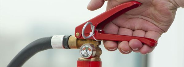 Hand pulling the red handle of a fire extinguisher.