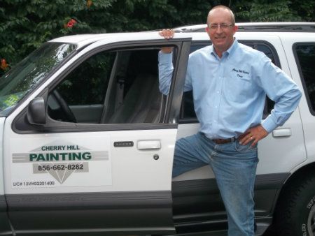 Man in blue shirt and jeans stands by white van with
