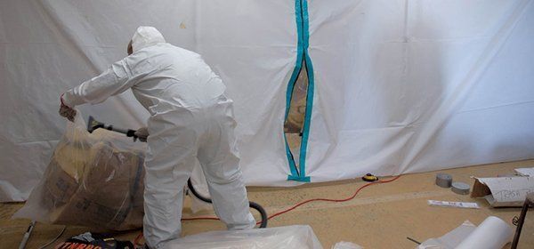a man in a protective suit is holding a vacuum in a room.