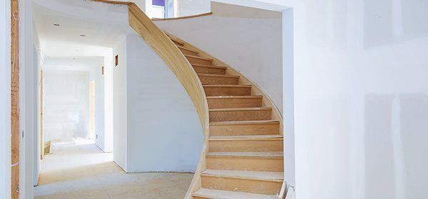 a wooden spiral staircase in a hallway in a house under construction .