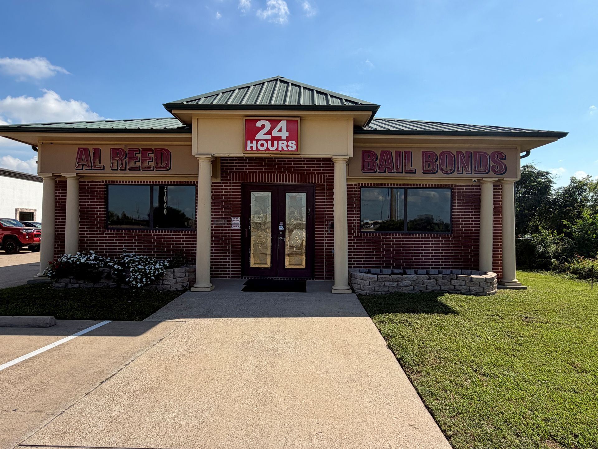 24 Hour Nails storefront with a brick facade, red sign, and sidewalk leading to the entrance