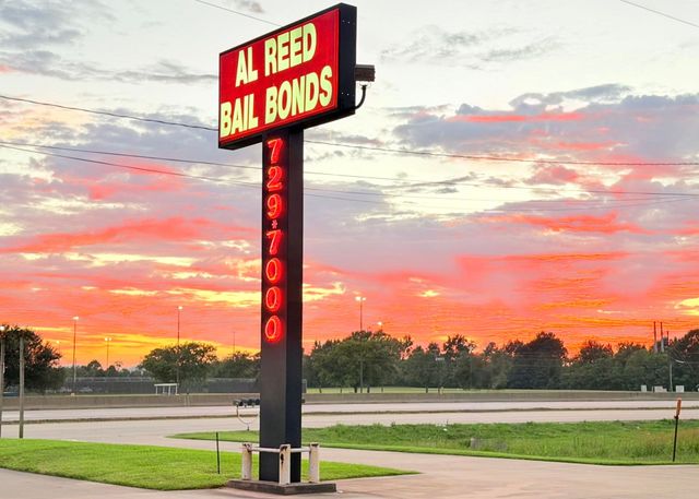 Al Reed Bail Bonds sign at sunset beside an empty roadside parking lot