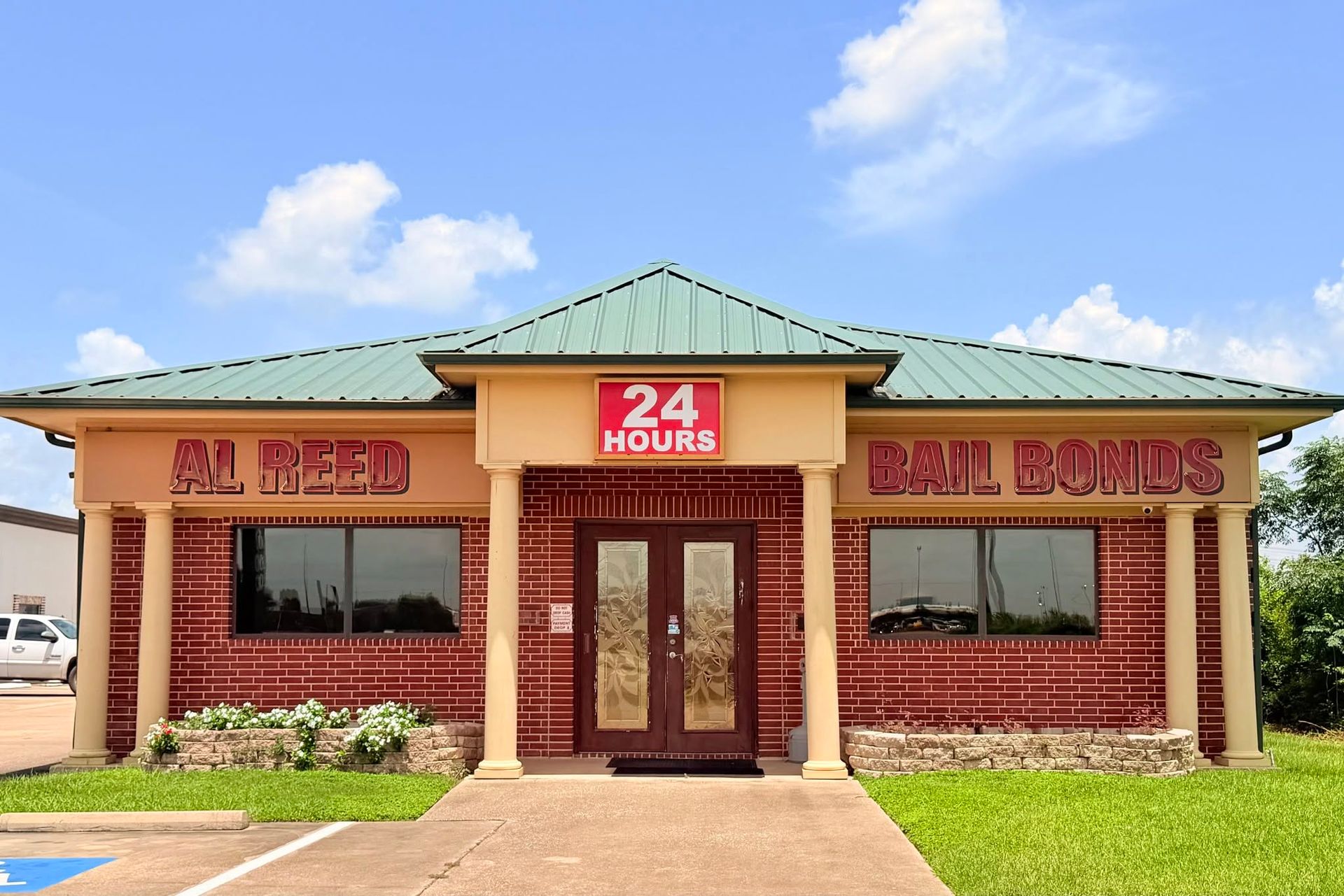 24-hour red-brick BBQ diner with green roof and double doors under a blue sky