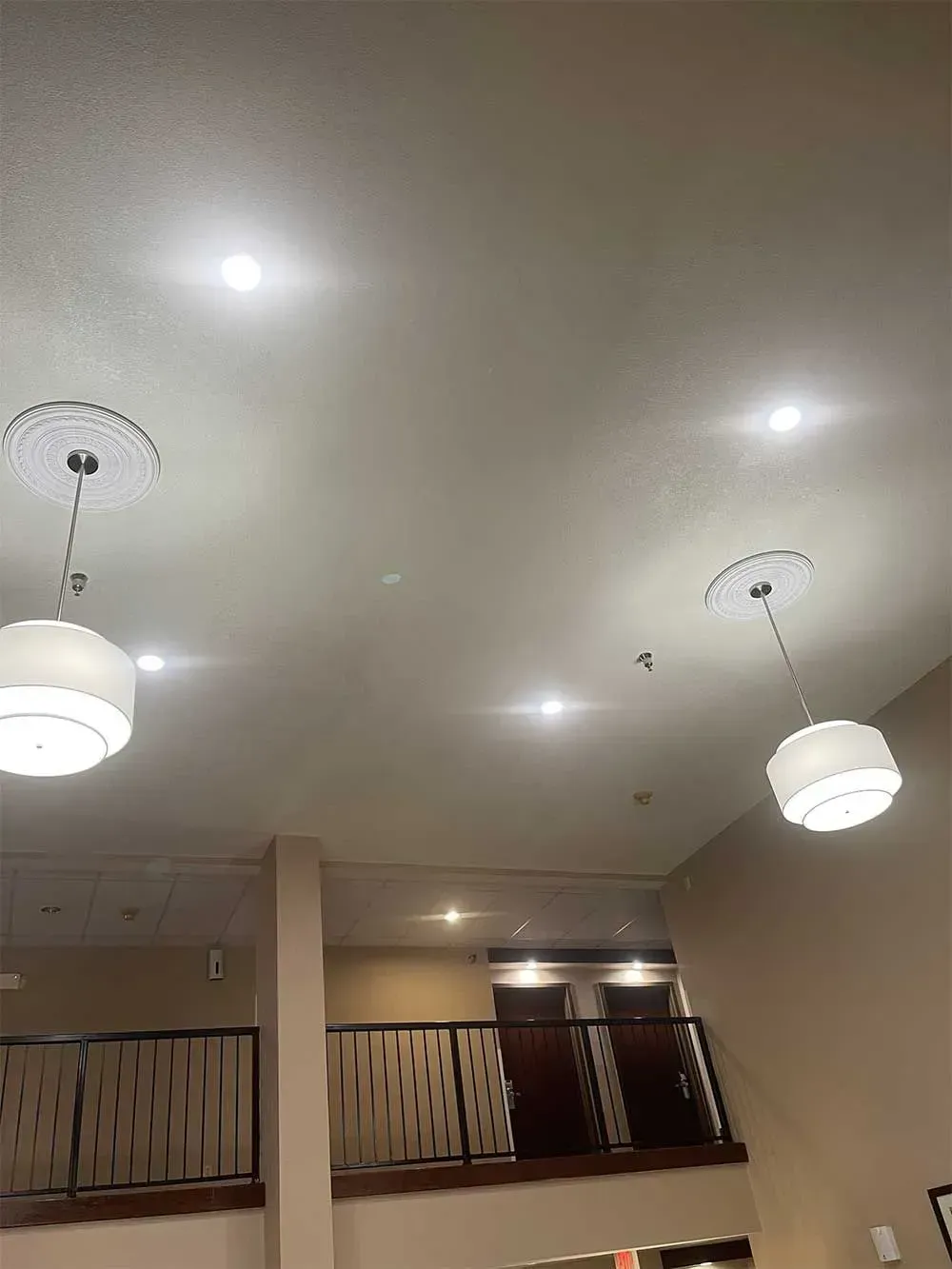 Two hanging pendant lights and recessed ceiling lights in a room with a balcony.