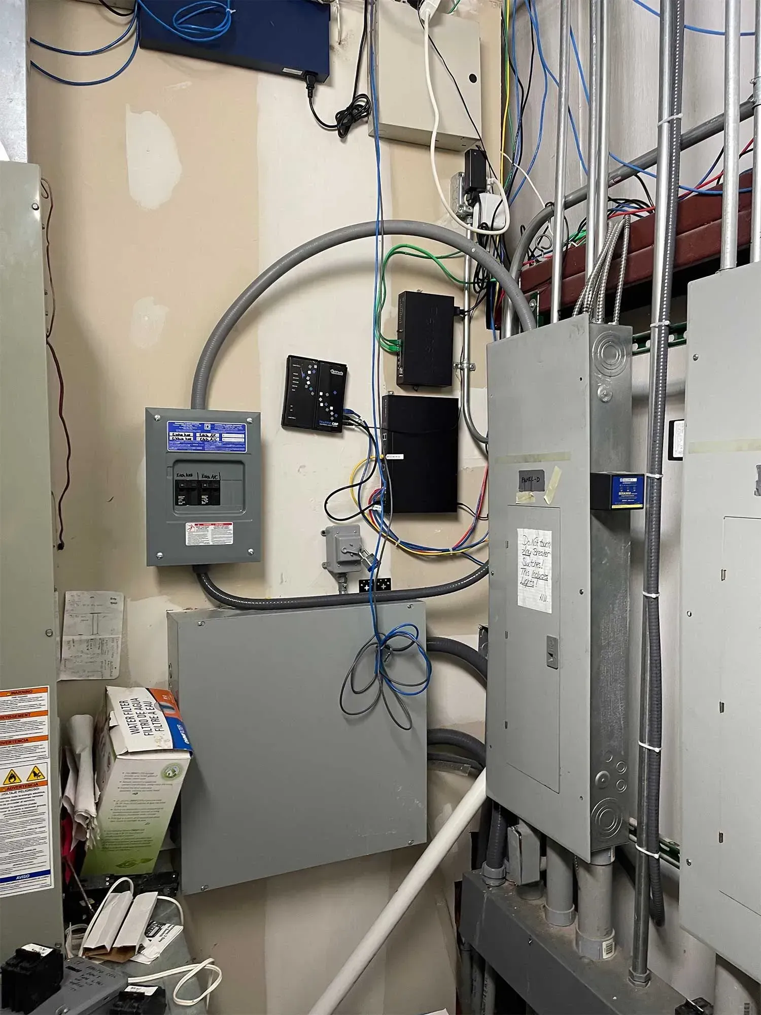 Electrical panel with wires and conduit against a wall; gray boxes and wires.