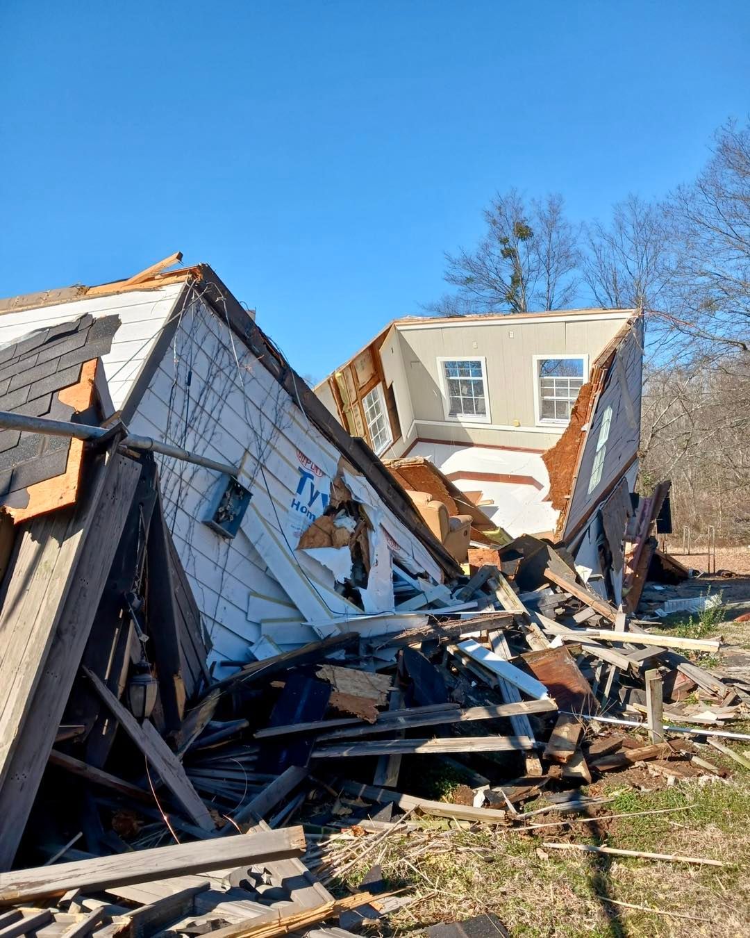 Damaged building debris, collapsed walls, and exposed interior against a blue sky.