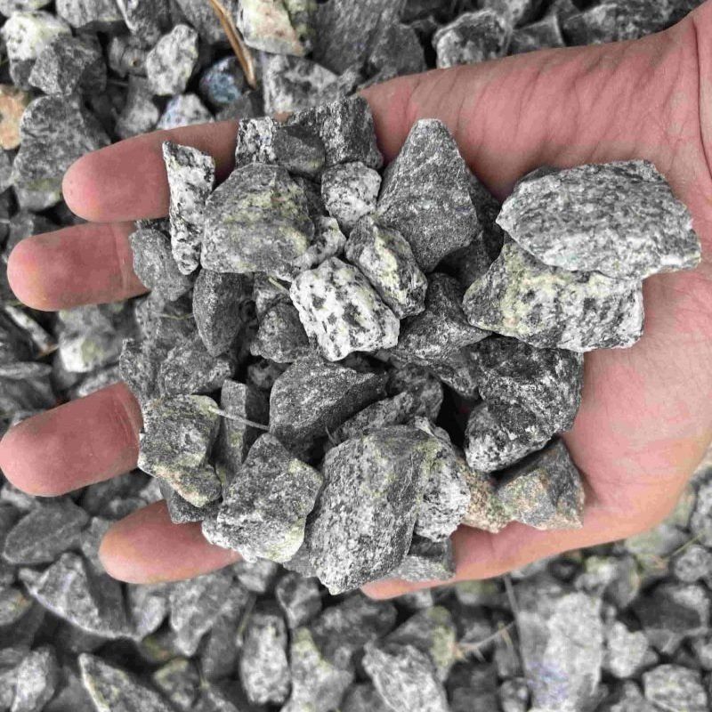 Hand holding a pile of gray gravel.