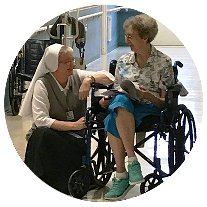 A nun is talking to an elderly woman in a wheelchair.