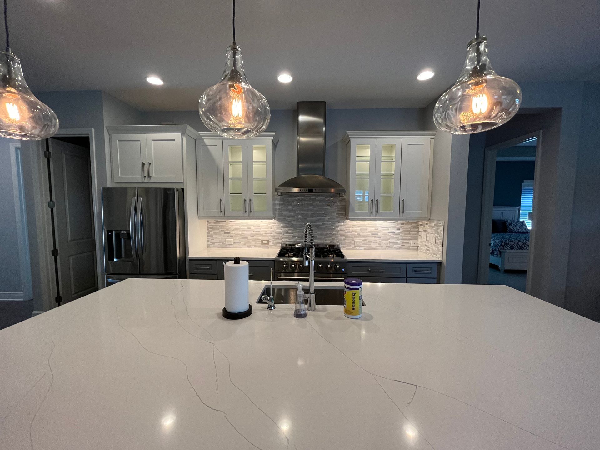 A kitchen with white cabinets , stainless steel appliances , a sink , and a large island.
