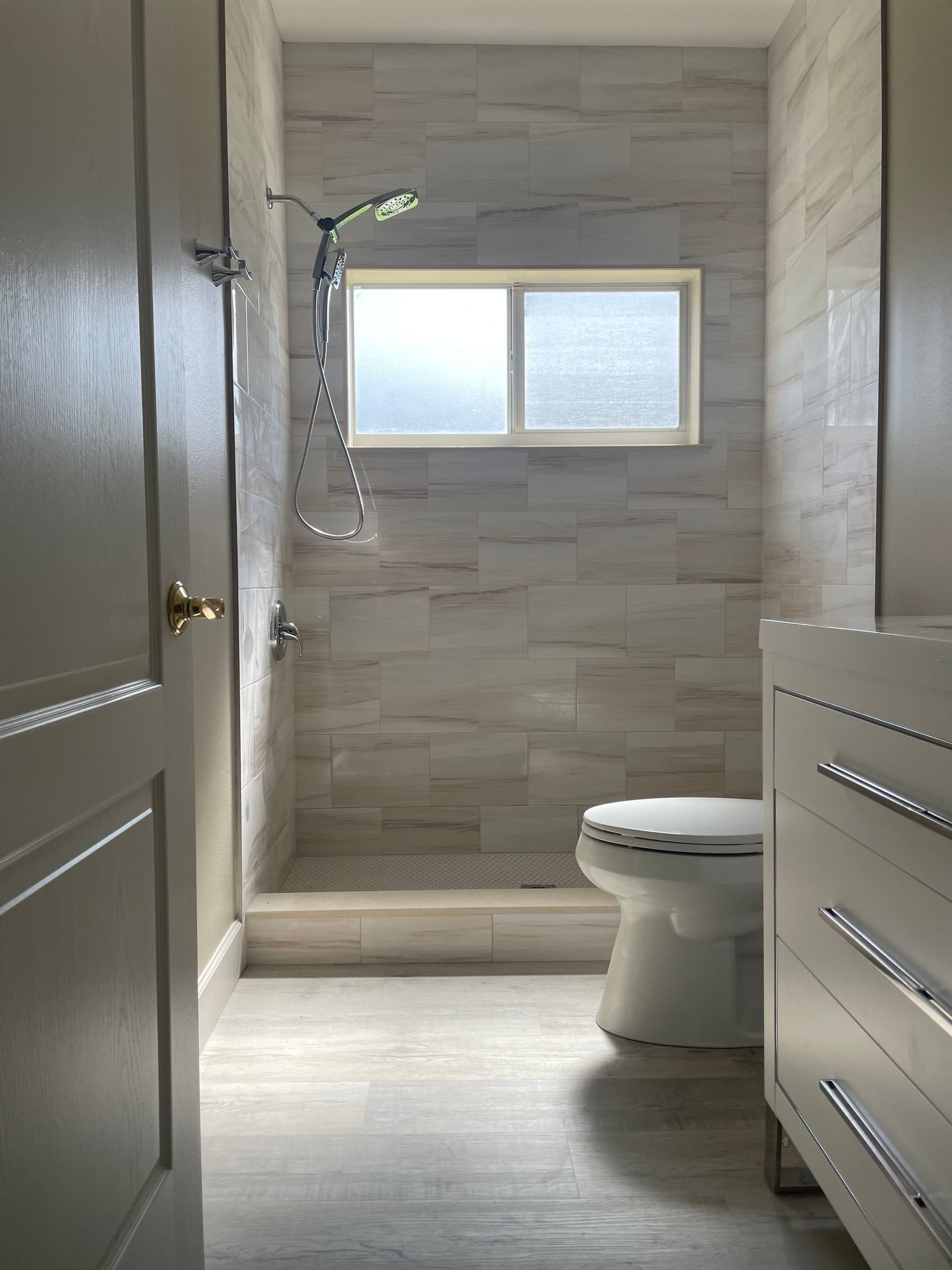 A bathroom with a toilet , sink , shower and window.