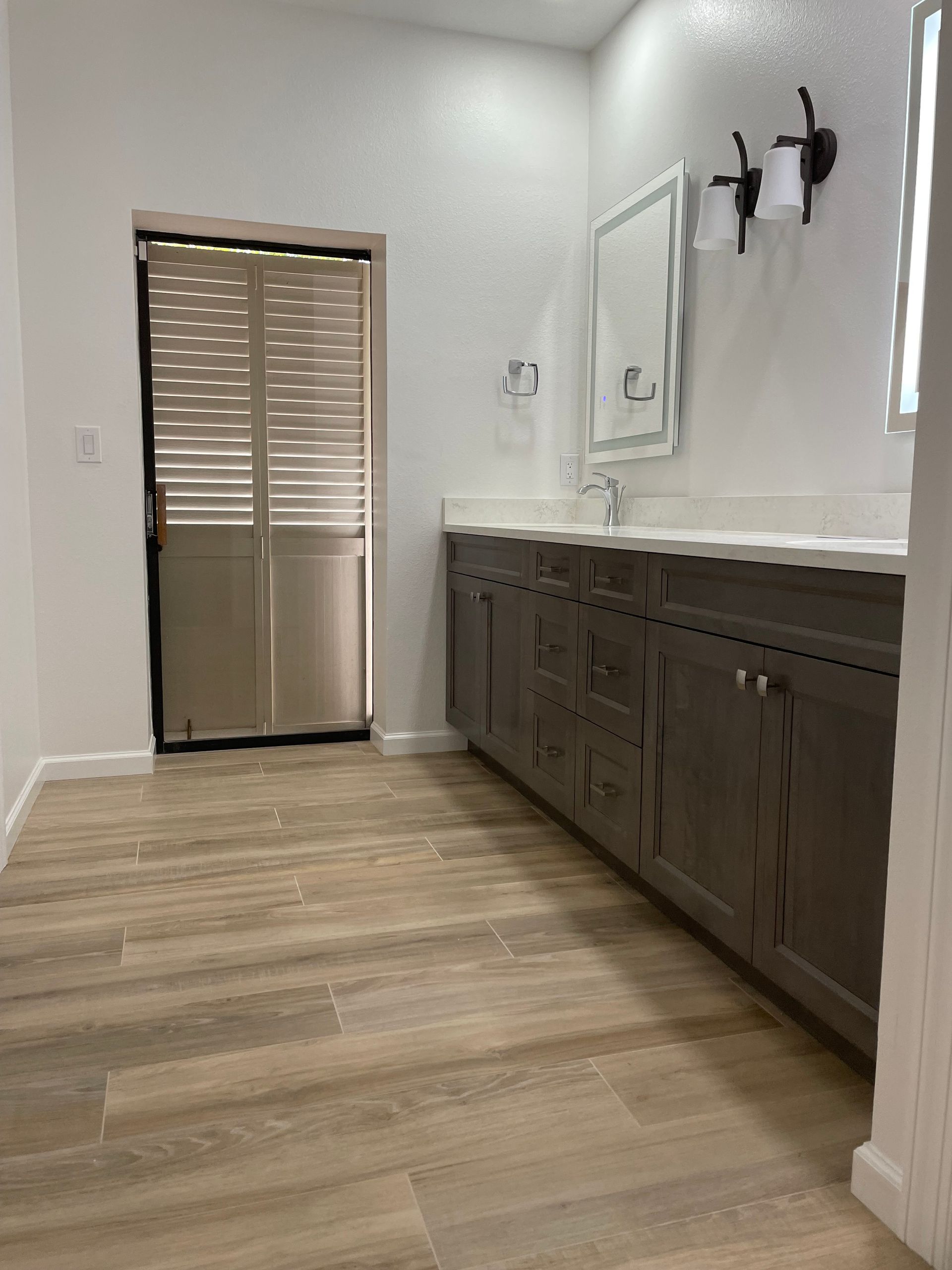 A bathroom with a sink , mirror and sliding glass door.