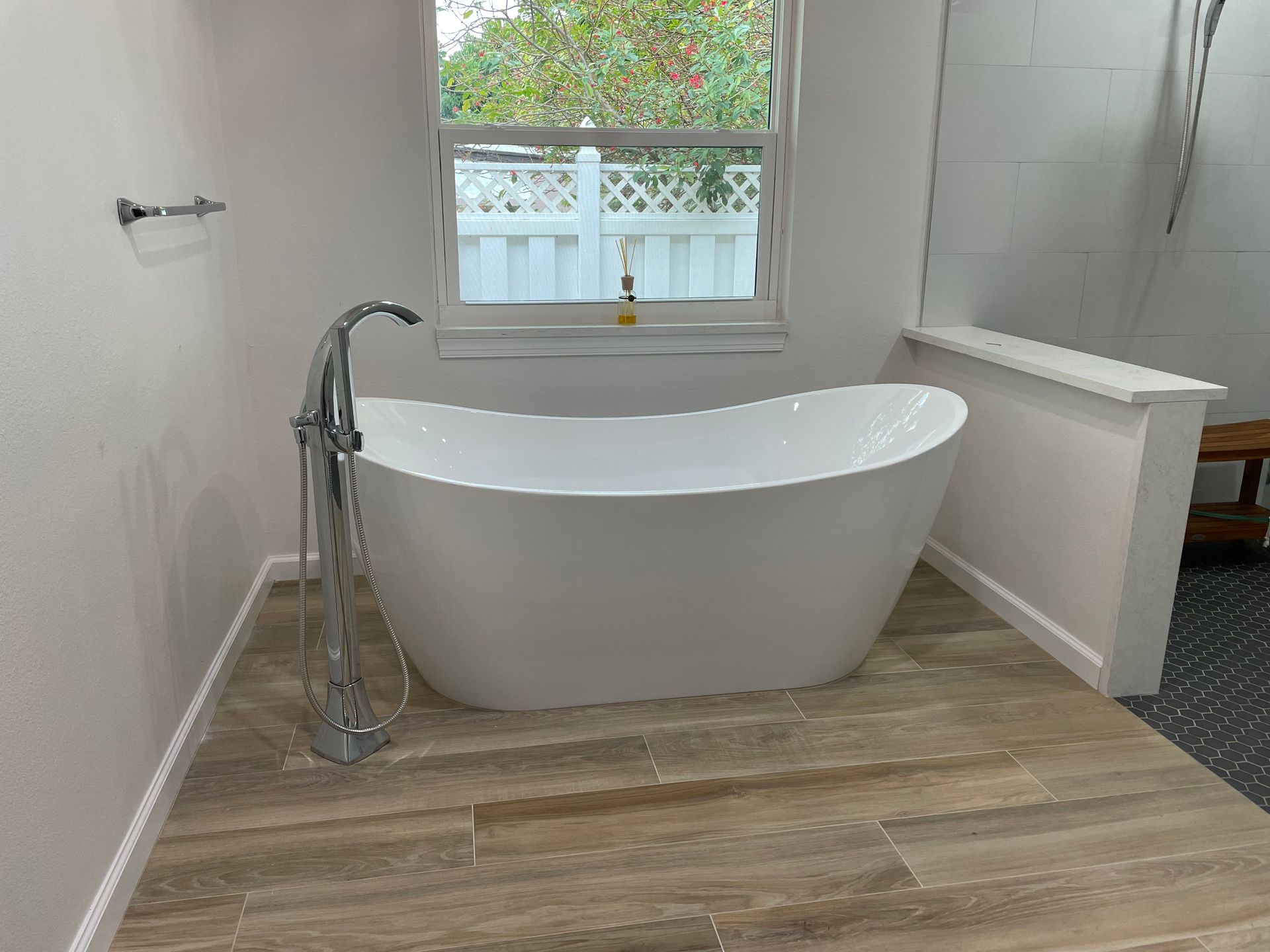 A white bathtub is sitting in a bathroom next to a window.