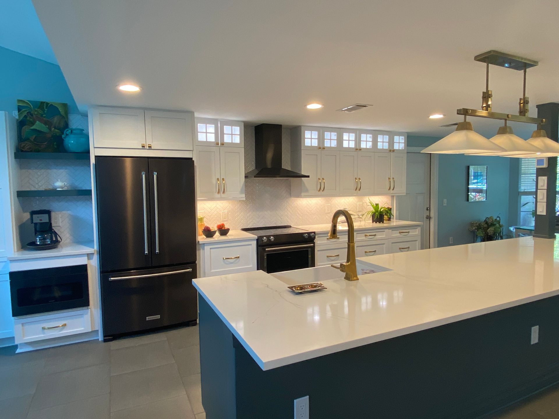 A kitchen with white cabinets , stainless steel appliances , and a large island.