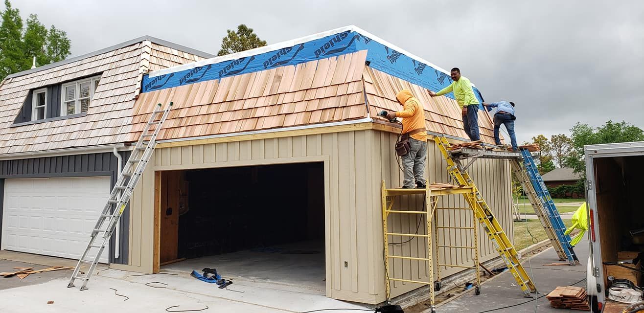 Roofers installing cedar shingles on a residential garage.