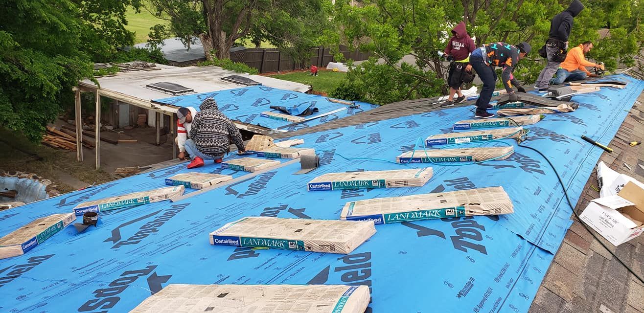Workers installing a roof, blue tarp and shingles visible.