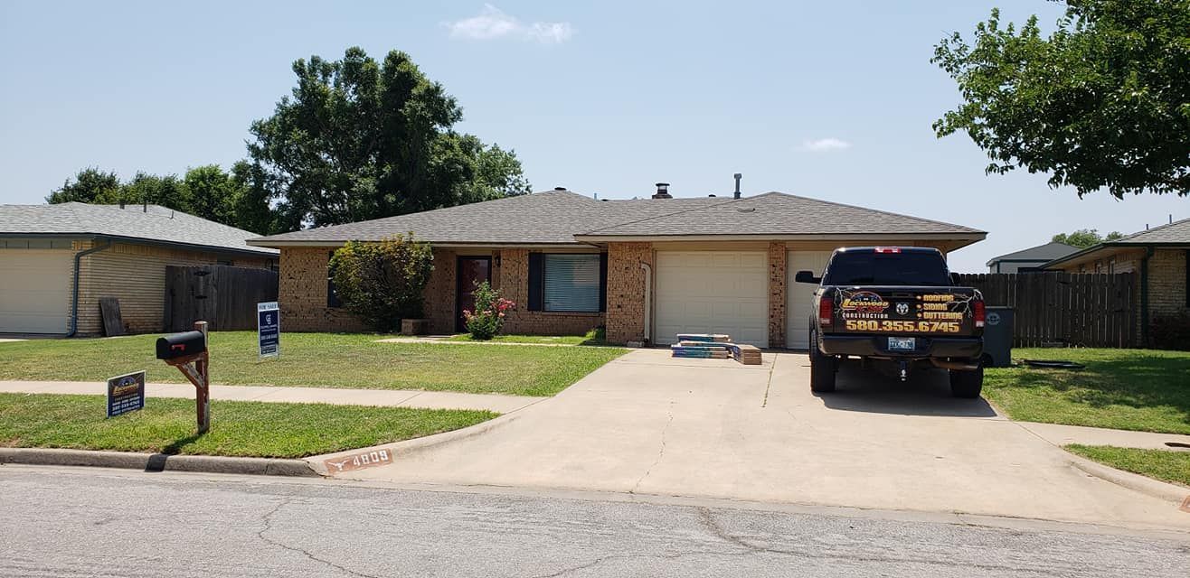 A suburban house with a truck parked in the driveway under a blue sky.