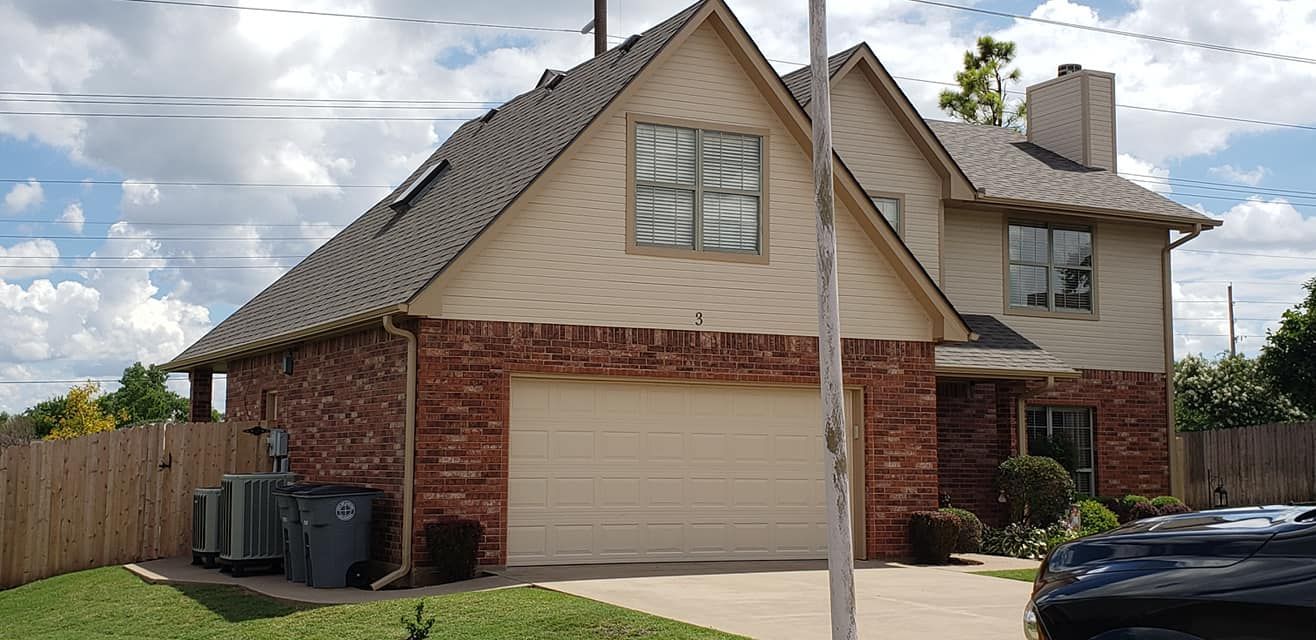 Two-story brick house with garage, beige siding, and a chimney.