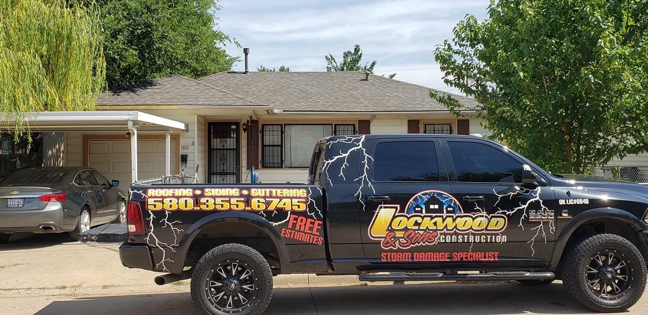 Black truck parked in front of a house; company logo with lightning bolts on the side.