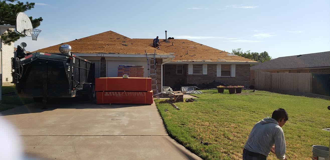 House roof being worked on. Dumpster in driveway, man in yard.