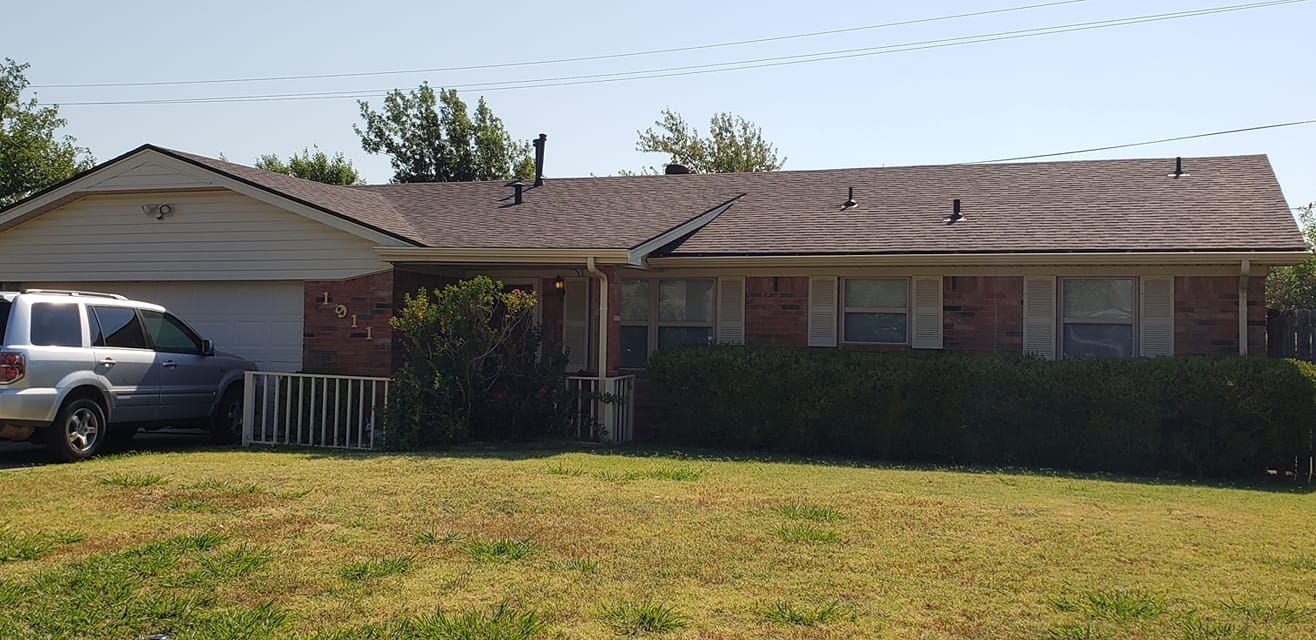 A one-story brick home with a garage and a gray SUV parked in the driveway.