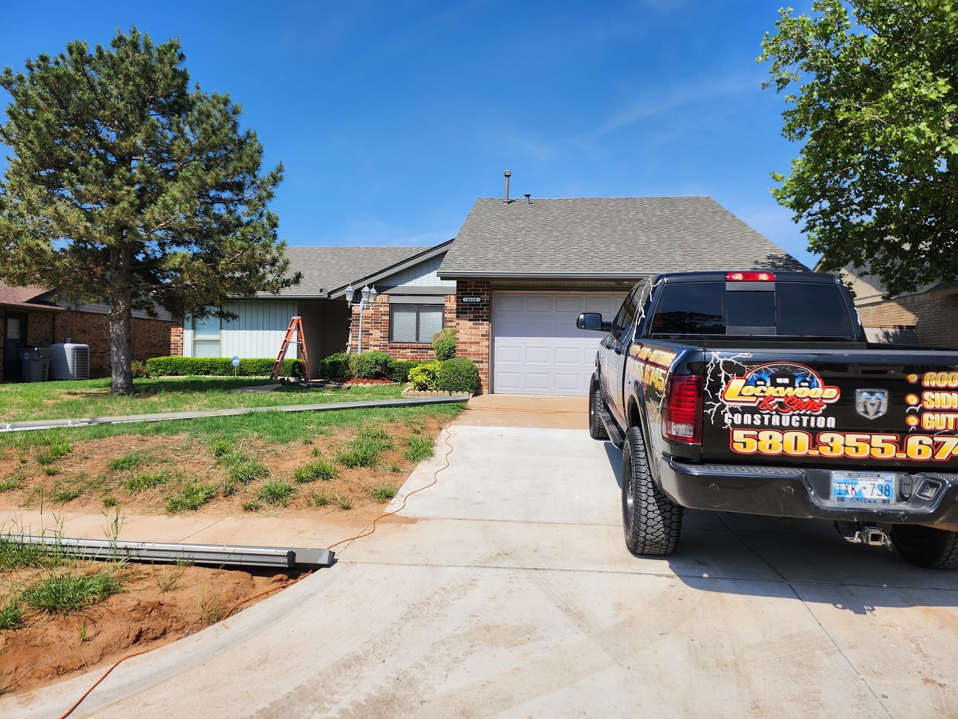 A black pickup truck parked in front of a one-story house with a gray roof.