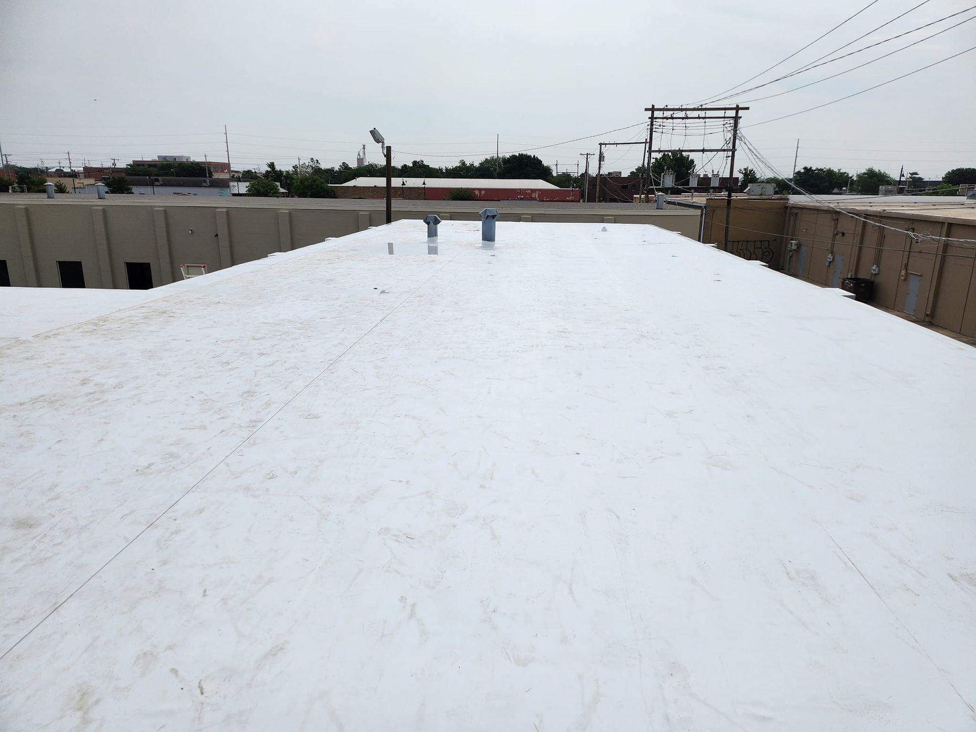 White commercial roof on an overcast day, overlooking a business area.