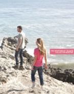 A man and a woman are standing on a rocky cliff overlooking the ocean.