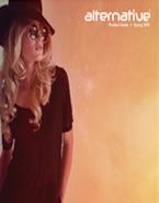 A woman wearing a hat and sunglasses is standing next to a wall.