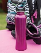 a pink water bottle is sitting on a pink yoga mat next to a pair of shoes .