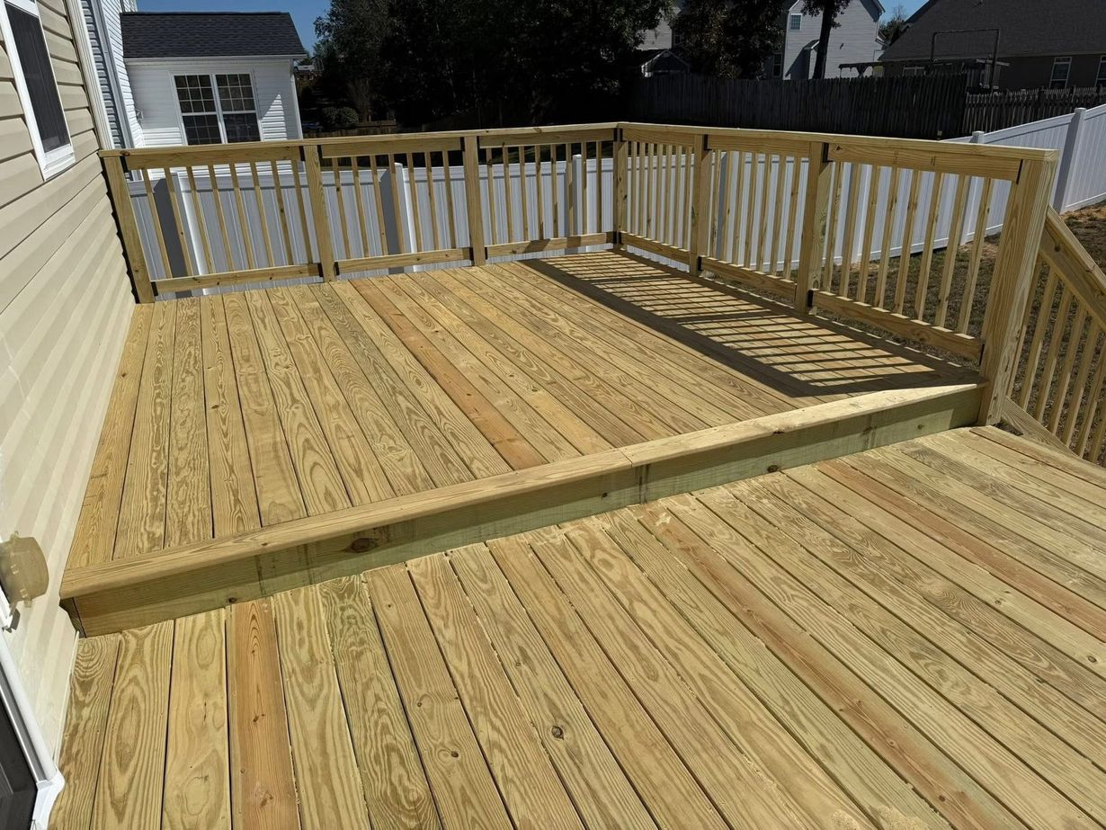 Wooden deck with railing and steps in a sunny backyard