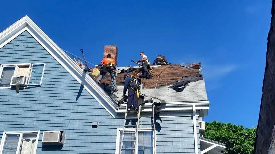 A group of people are working on the roof of a house.