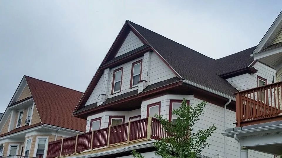 A white house with a brown roof and a balcony
