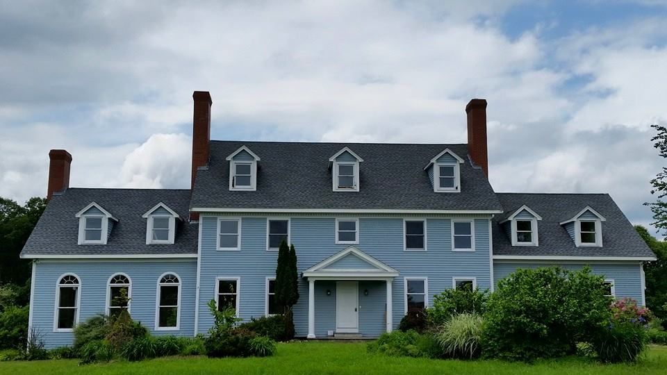 A large blue house with a gray roof and chimneys