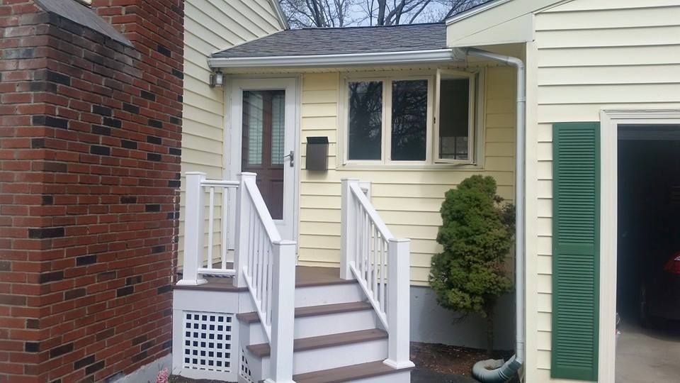 A yellow house with a white porch and stairs