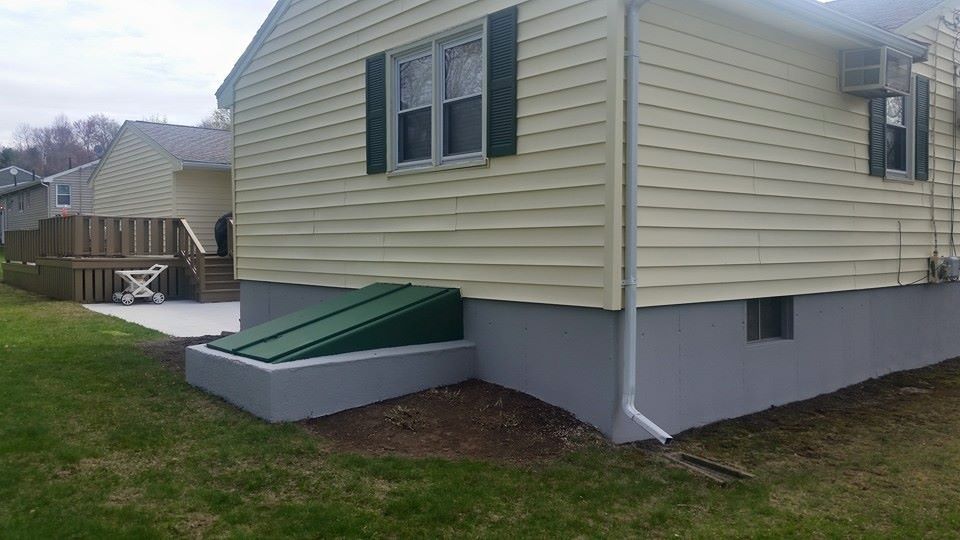 The back of a house with a green door and a drainpipe.