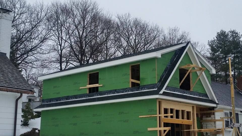 A green house with a black roof is being built.