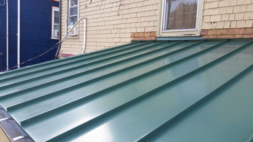 A green metal roof is sitting on top of a brick building.