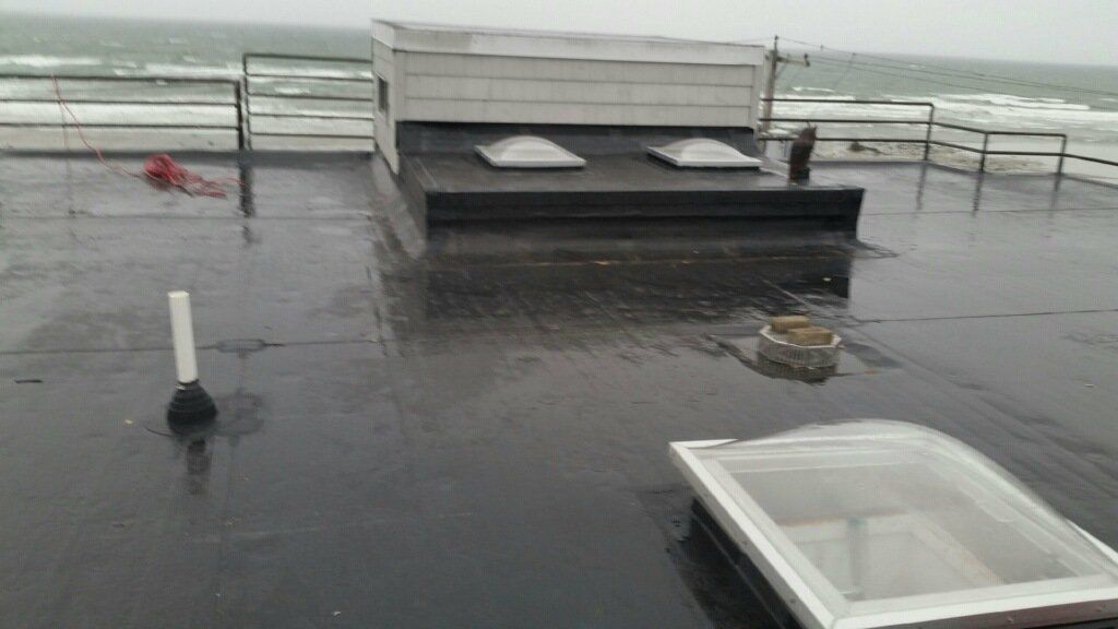 A roof with a skylight on it and a view of the ocean.