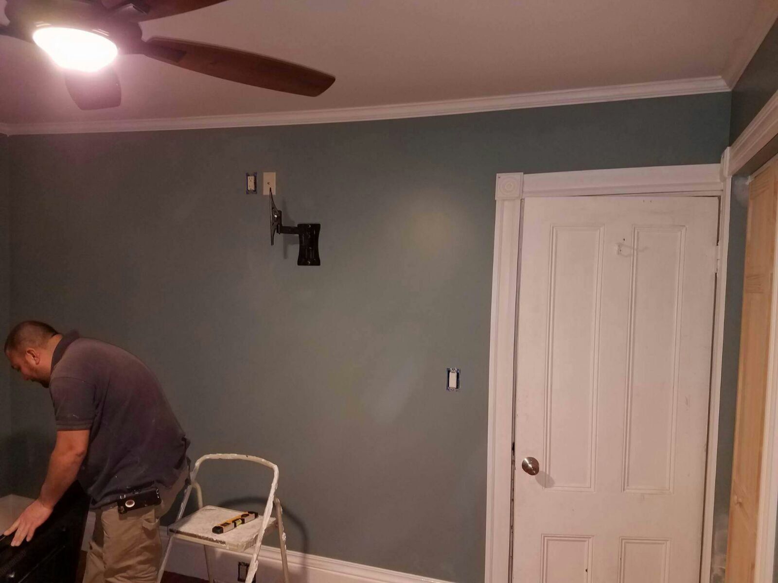 A man is standing in a room with a ceiling fan.
