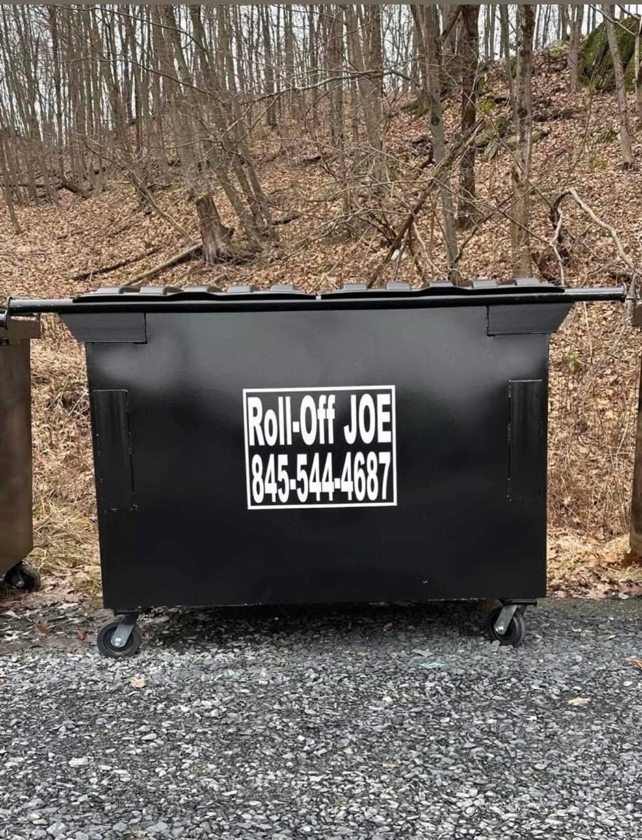Black dumpster on wheels labeled 
