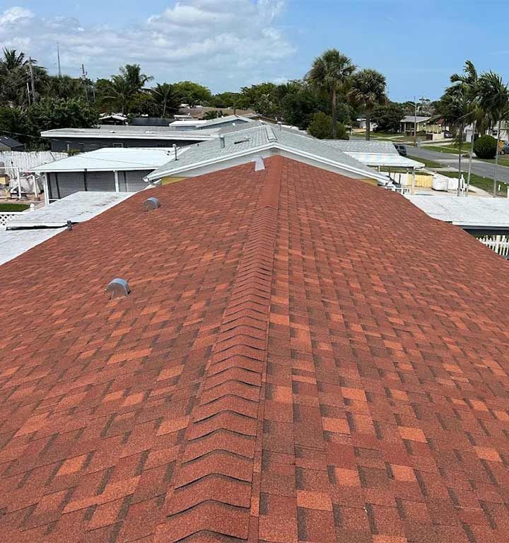 The roof of a house with a red shingle roof.