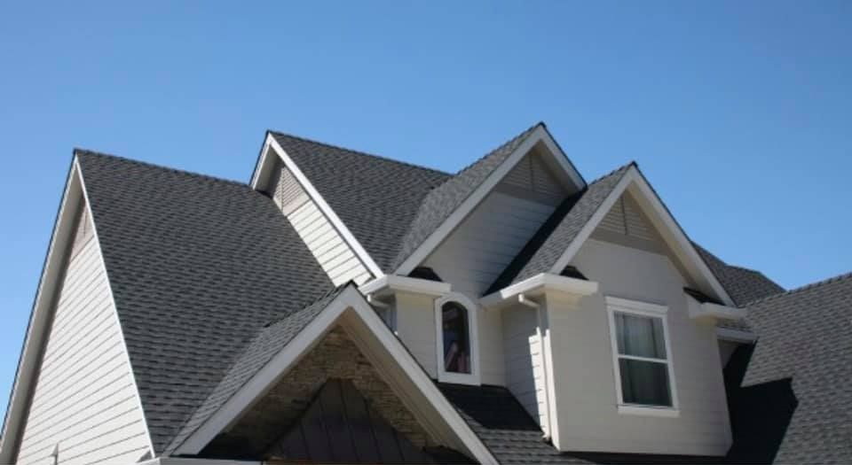 A white house with a gray roof and a blue sky in the background.