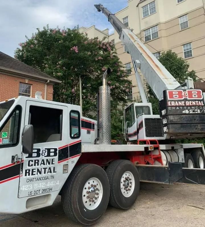 Crane truck from B&B Crane Rental in Chattanooga, TN, near a building.