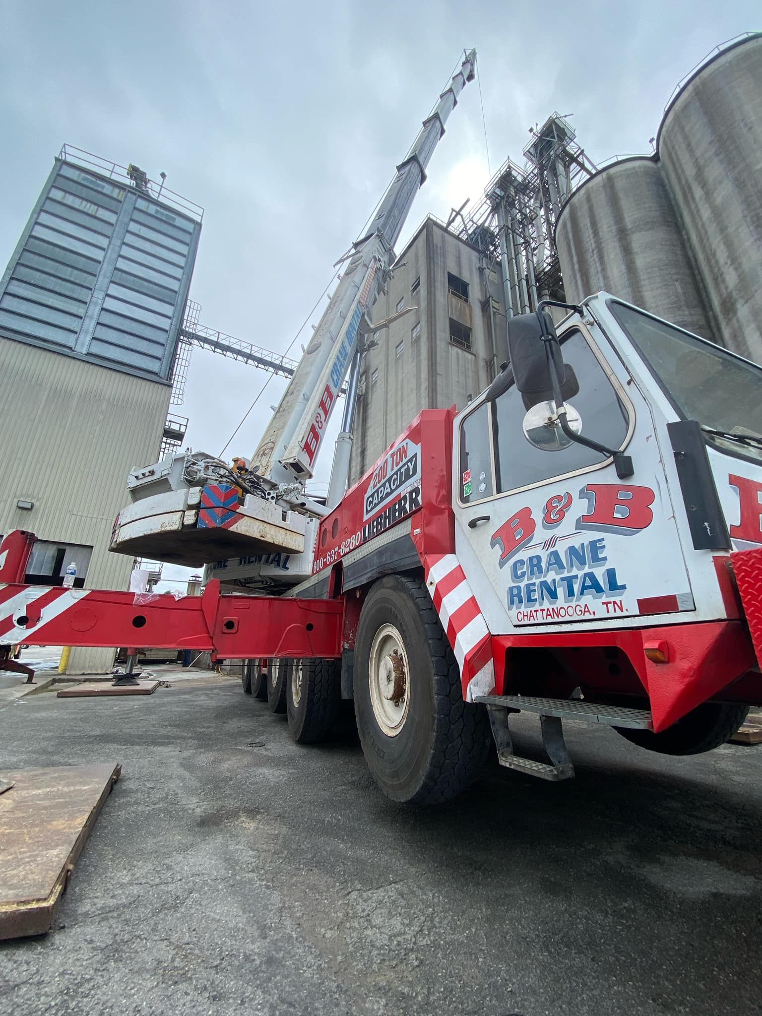 A large red and white crane is parked in front of a building.