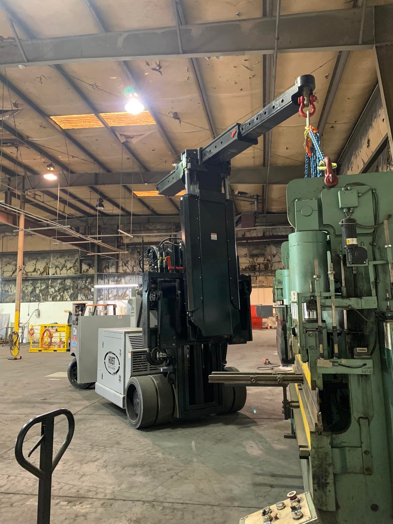 A forklift is moving a machine in a factory.