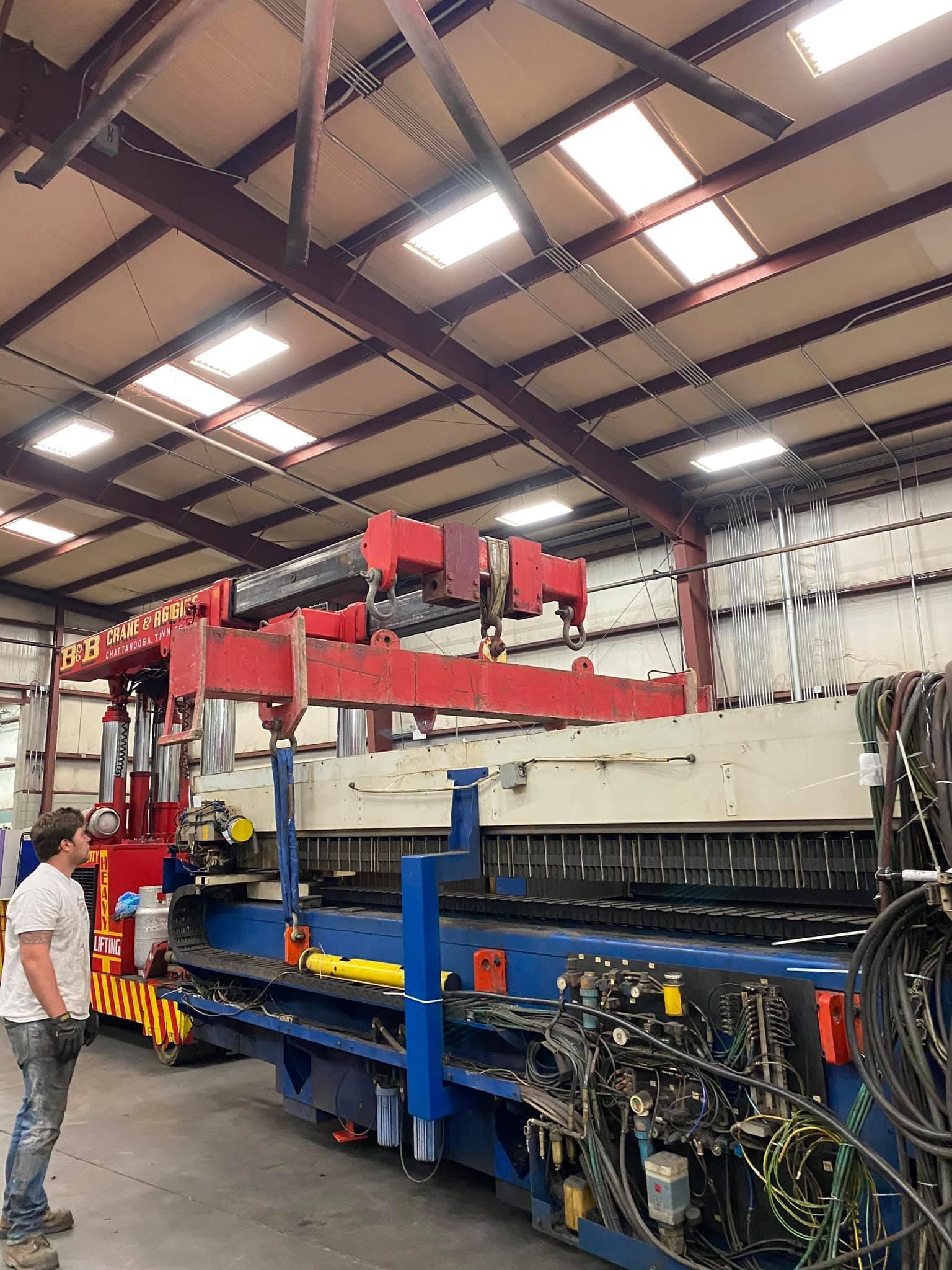 A man is standing in front of a machine in a factory.